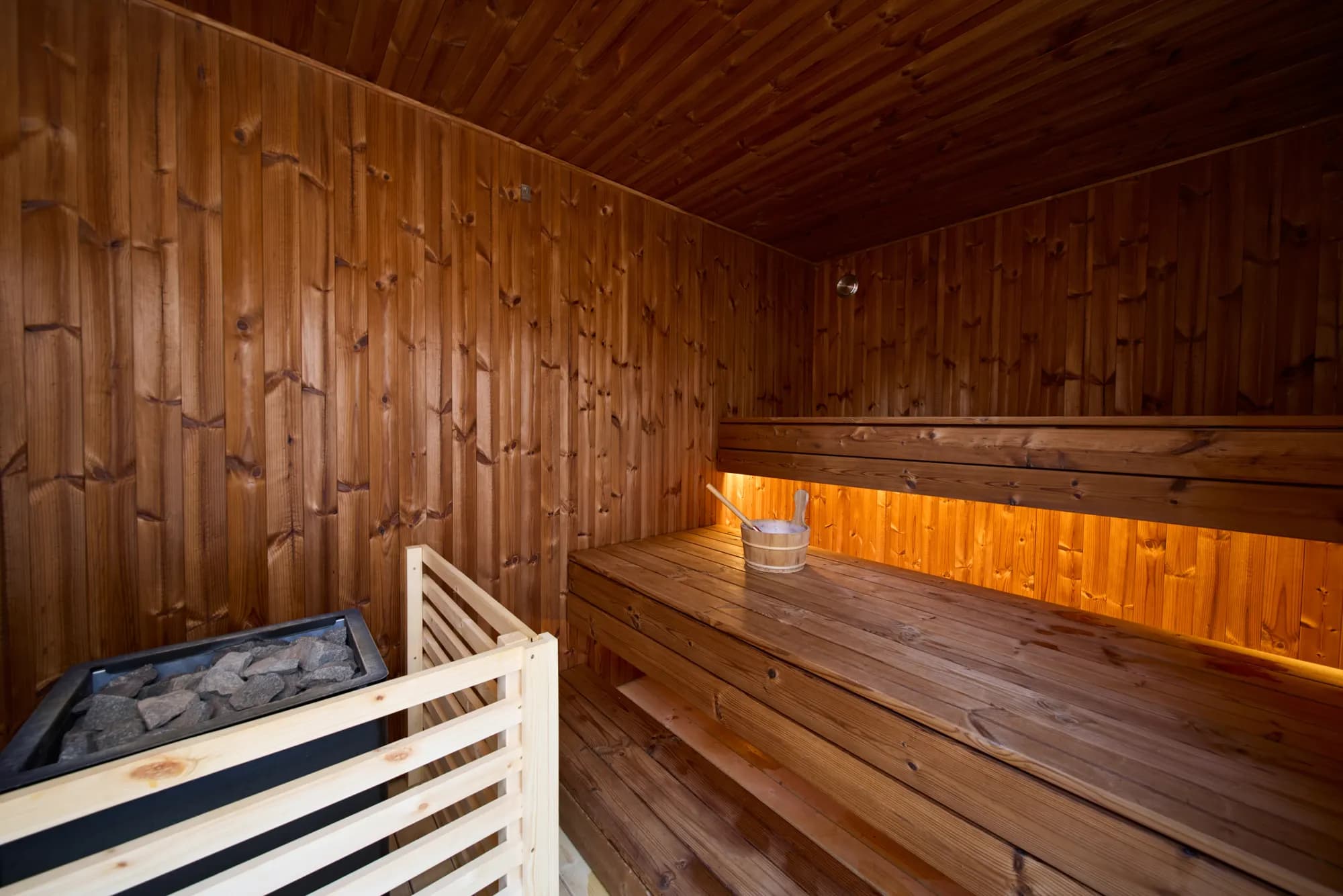 Warm-lit spruce benches inside a Finnish sauna